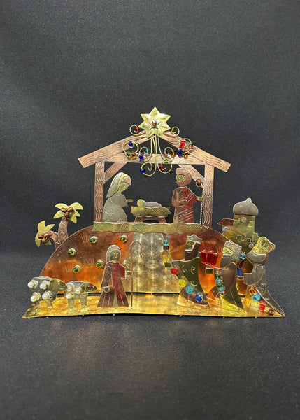 A standing nativity set made of mixed metals with colorful beading, featuring figures on a golden base with a star at the top.