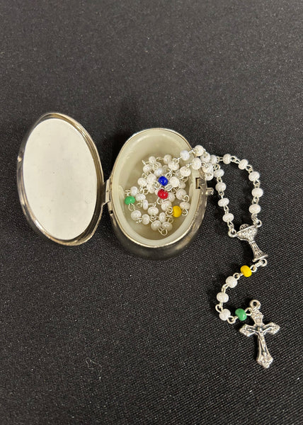 Rosary with colorful beads in an open silver locket on a black background