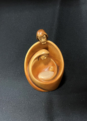 A wood carved and hand painted nativity set depicting the nativity scene, natural colors, placed against a black background.