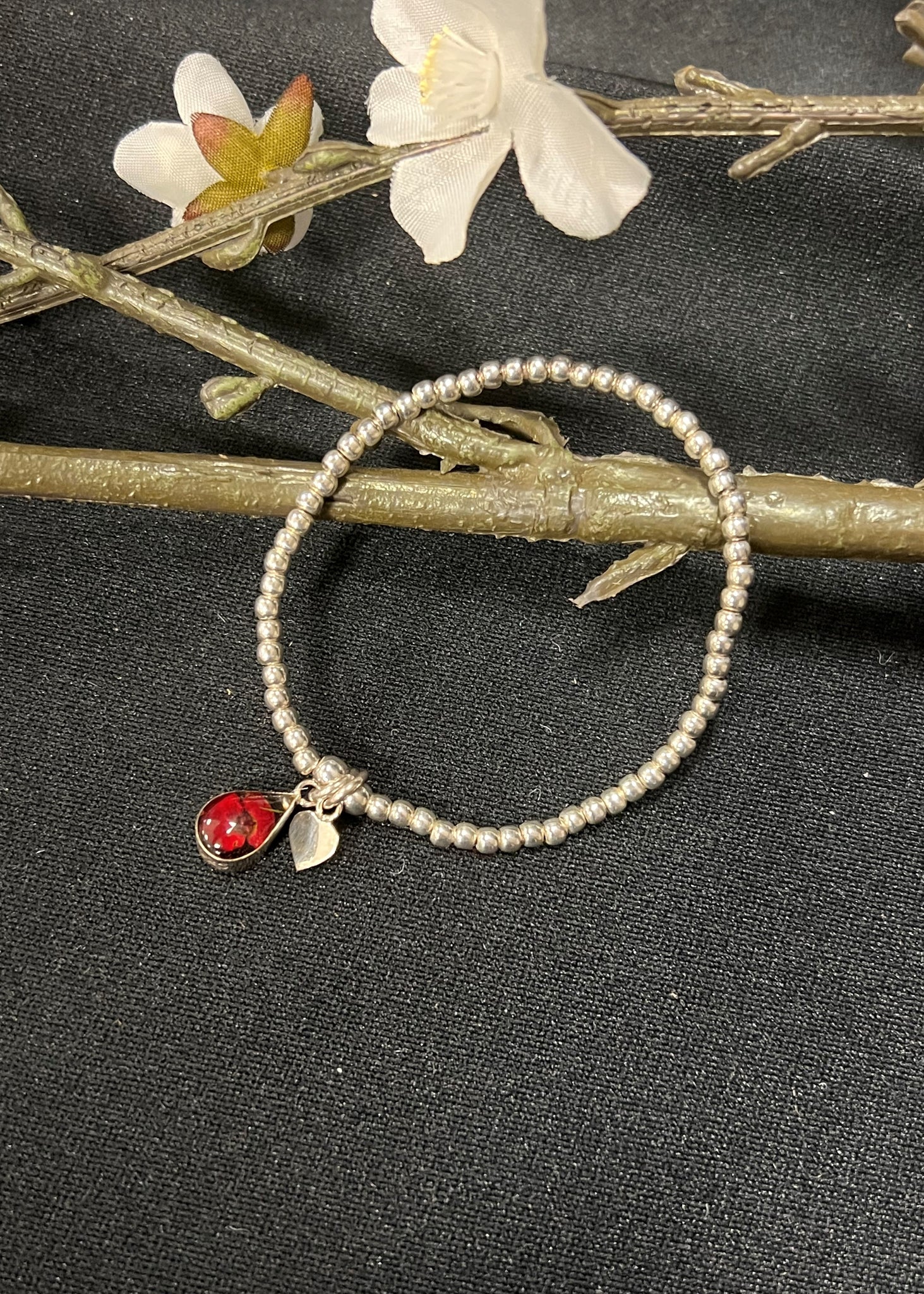 A sterling silver bracelet with a real poppy flower charm.