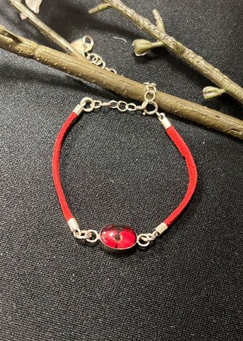 A red faux suede strap bracelet with a sterling silver chain and a real poppy flower charm.